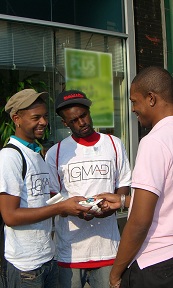 Two men in GMAD T-shirts giving information to another man Two men in GMAD T-shirts giving information to another man